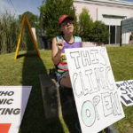 
              Clinic escort Ren Allen of Jackson, calls out to incoming patients that the Jackson Women's Health Organization clinic is open in Jackson, Miss., Saturday, June 25, 2022. The clinic is the only facility that performs abortions in the state. However, the U.S. Supreme Court overturned Roe v. Wade, ending constitutional protections for abortion. (AP Photo/Rogelio V. Solis)
            