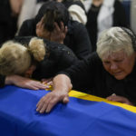 
              The mother, right, and sister of Army Col. Oleksander Makhachek mourn over the coffin with his remains during a funeral service in Zhytomyr, Ukraine, Friday, June 3, 2022. According to combat comrades Makhachek was killed fighting Russian forces when a shell landed in his position on May 30. (AP Photo/Natacha Pisarenko)
            
