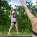 
              Lucy Wright, 5, struts and poses with her mother, Michelle Wright, on Monday, June 13, 2022, at Boyce Park wave pool in Plum, Pa. Lucy is named after Lucille Ball, actress who played Lucy Ricardo on the show "I Love Lucy" and who is well-known for her facial expressions. (Ariana Shchuka/Pittsburgh Post-Gazette via AP)
            