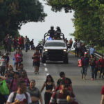 
              Miembros de la Guardia Nacional avanzan junto a migrantes por la carretera hacia la salida a Huixtla, estado de Chiapas, México, la madrugada del jueves 9 de junio de 2022. El grupo de migrantes salió de Tapachula el lunes, cansado de esperar para normalizar su estatus en una región con poco trabajo, con el objetivo de llegar a Estados Unidos (AP Foto/Marco Ugarte)
            