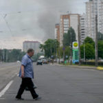 
              A man crosses a street as smoke rises in the background after Russian missile strikes in Kyiv, Ukraine, Sunday, June 5, 2022. (AP Photo/Natacha Pisarenko)
            