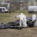 
              FILE - Men wearing protective gear carry a dead body during the exhumation of killed civilians in Bucha, outskirts of Kyiv, Ukraine, Friday, April 8, 2022. Police are investigating the killings of more than 12,000 Ukrainians nationwide in the war Russia is waging, the national police chief said Monday. In the Kyiv region near Bucha, authorities showed several victims whose hands were tied behind their backs. (AP Photo/Efrem Lukatsky, FILE)
            