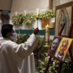 
              A priest blesses the photos of Jesuit priests Javier Campos Morales, left, and Joaquin Cesar Mora Salazar during a Mass to mourn them, at a church in Mexico City, Tuesday, June 21, 2022. The two elderly priests were killed inside a church where a man pursued by gunmen apparently sought refuge in a remote mountainous area of northern Mexico, the religious order’s Mexican branch announced Tuesday. (AP Photo/Fernando Llano)
            