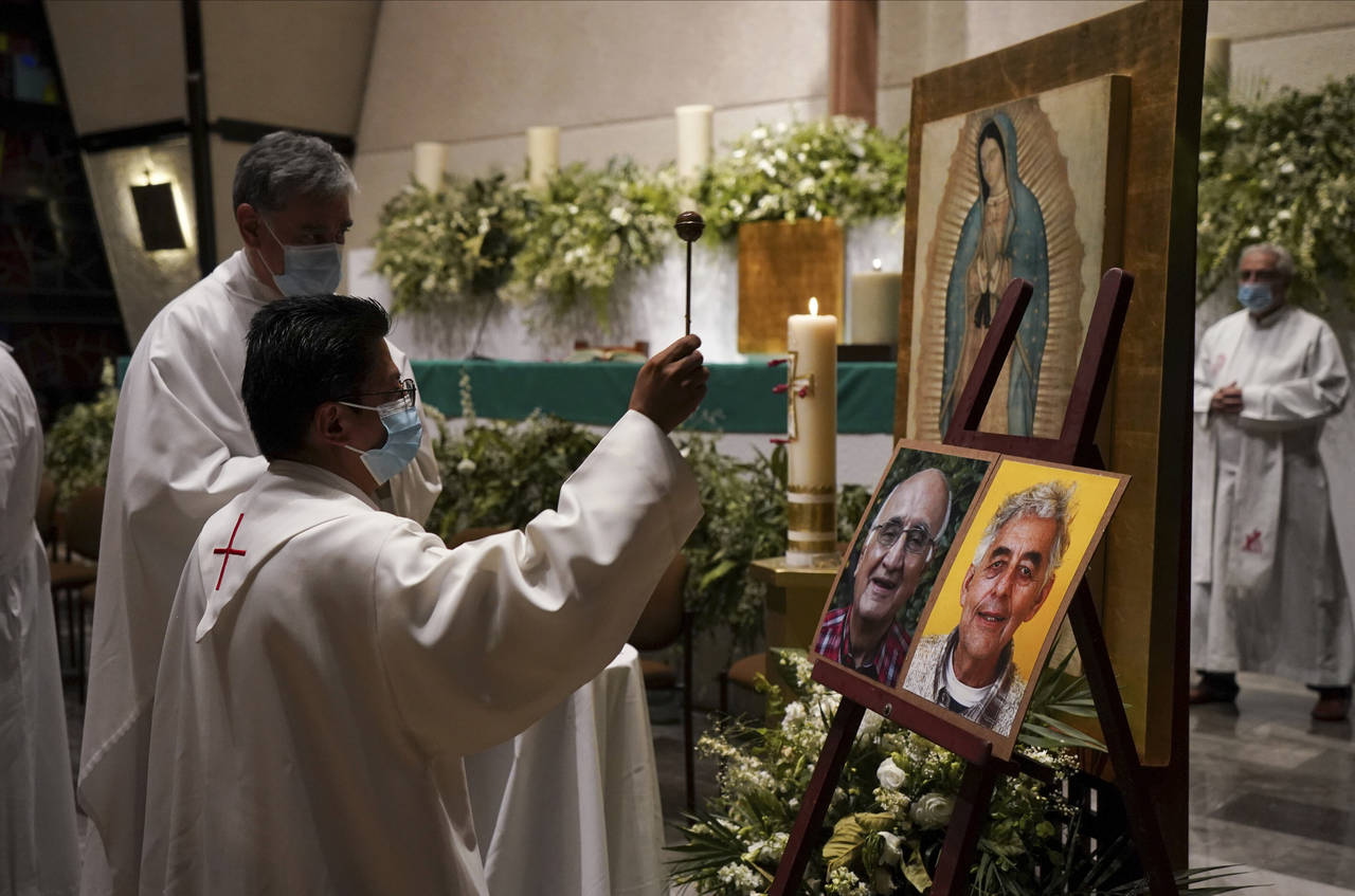 A priest blesses the photos of Jesuit priests Javier Campos Morales, left, and Joaquin Cesar Mora S...