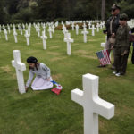 
              Alice, let, puts a flower, as family members Remy, Dalma and Sylvie, from left to right, look on, in the 1944 headstones of the US cemetery of Colleville-sur-Mer, Normandy, Saturday, June, 4, 2022. Several ceremonies will take place to commemorate the 78th anniversary of D-Day that led to the liberation of France and Europe from the German occupation. (AP Photo/Jeremias Gonzales)
            