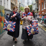 
              Two women attend a public street party in Castle Lane in central London, Sunday June 5, 2022, on the last of four days of celebrations to mark the Platinum Jubilee. Street parties are set to be held across the country in what is being called The Big Jubilee Lunch. The events over a long holiday weekend in the U.K. have celebrated Queen Elizabeth II's 70 years of service. (AP Photo/David Cliff)
            