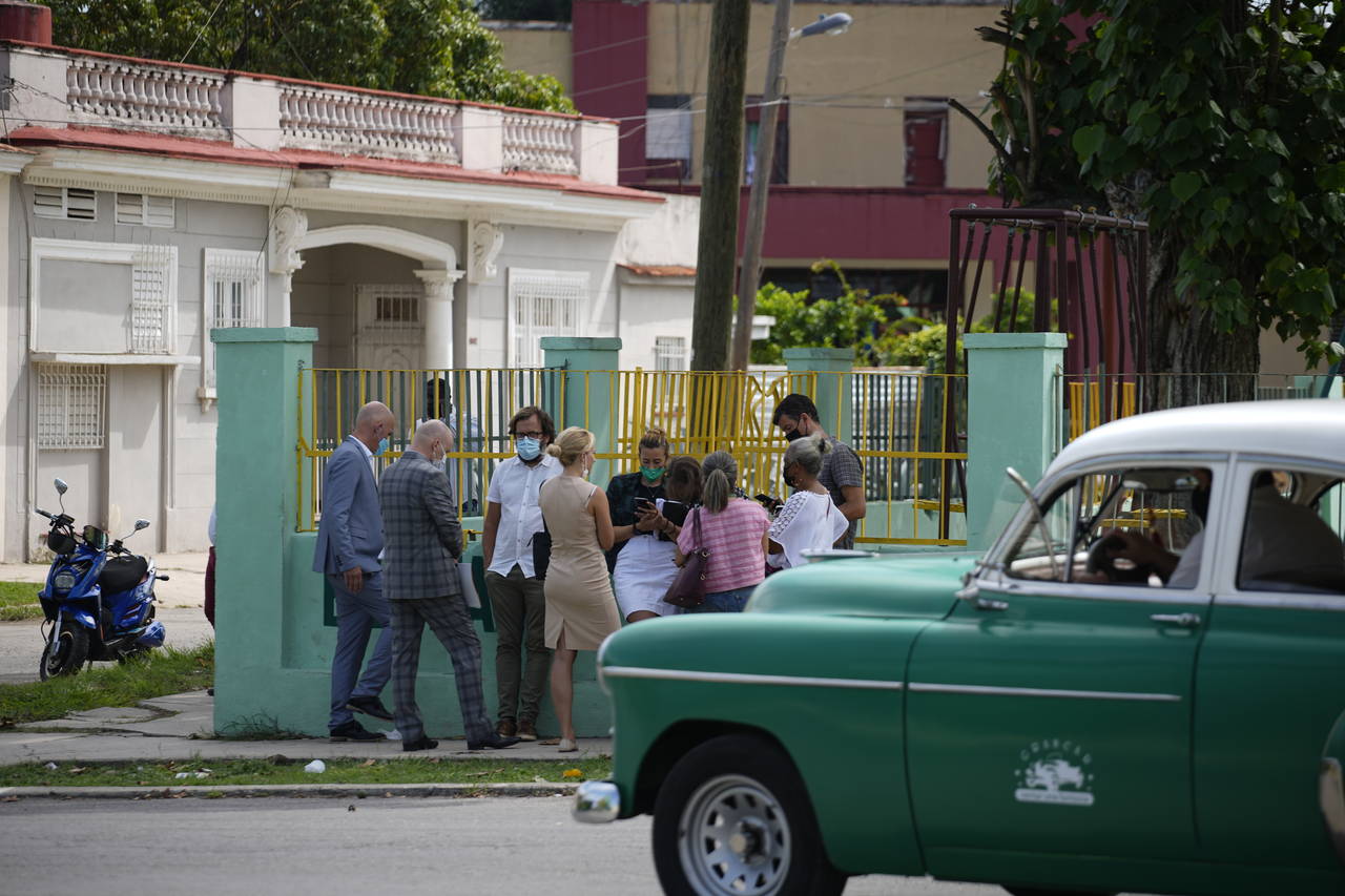 Diplomats from several countries wait outside the court building where a trial is going on for Cuba...