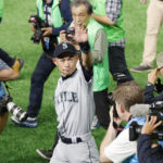 
              AP Photographer Toru Takahashi is seen at rear as Seattle Mariners right fielder Ichiro Suzuki waves to fans after returning to the field after Game 2 of the Major League baseball opening series against the Oakland Athletics at Tokyo Dome in Tokyo, on March 21, 2019.  Takahashi, a Tokyo-based photo editor and photographer for The Associated Press who spent his long career meticulously capturing images and sharing his wealth of knowledge with colleagues, has died. He was 62.(Kyodo News via AP)
            