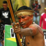 
              An indigenous man aims an arrow during a protest against the disappearance of Indigenous expert Bruno Pereira and freelance British journalist Dom Phillips, in Atalaia do Norte, Vale do Javari, Amazonas state, Brazil, Monday, June 13, 2022. Brazilian police are still searching for Pereira and Phillips, who went missing in a remote area of Brazil's Amazon a week ago. (AP Photo/Edmar Barros)
            