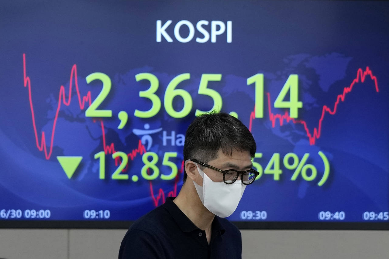 A currency trader walks by the screen showing the Korea Composite Stock Price Index (KOSPI) at a fo...