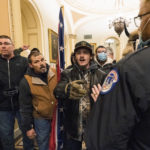 
              FILE - Kevin Seefried, second from left, holds a Confederate battle flag as he and other insurrectionists loyal to President Donald Trump are confronted by U.S. Capitol Police officers outside the Senate Chamber inside the Capitol in Washington, Jan. 6, 2021. A federal judge on Wednesday, June 15, 2022, convicted Kevin Seefried and his adult son Hunter Seefried of charges that they stormed the U.S. Capitol together to obstruct Congress from certifying President Joe Biden’s 2020 electoral victory. (AP Photo/Manuel Balce Ceneta, File)
            