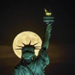 
              The Strawberry Supermoon rises in front of the Statue of Liberty in New York, late Tuesday, June 14, 2022. (AP Photo/J. David Ake)
            
