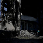 
              A woman walks past a building destroyed in Russian shelling in Borodyanka, on the outskirts of Kyiv, Ukraine, Tuesday, June 21, 2022. (AP Photo/Natacha Pisarenko)
            