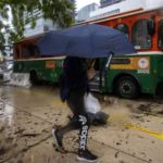 
              A person holds up an umbrella to guard against a light rain as cars and buses sit stalled  due to flooding on Southwest First Avenue in the Brickell neighborhood of Miami, Saturday, June 4, 2022. (Daniel A. Varela/Miami Herald via AP)
            
