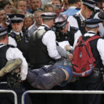 
              Police officers remove a man who ran into the path of the royal procession on The Mall, London, ahead of the Trooping the Color ceremony in London, Thursday June 2, 2022, on the first of four days of celebrations to mark the Platinum Jubilee. The events over a long holiday weekend in the U.K. are meant to celebrate the monarch's 70 years of service. (AP Photo/David Cliff)
            