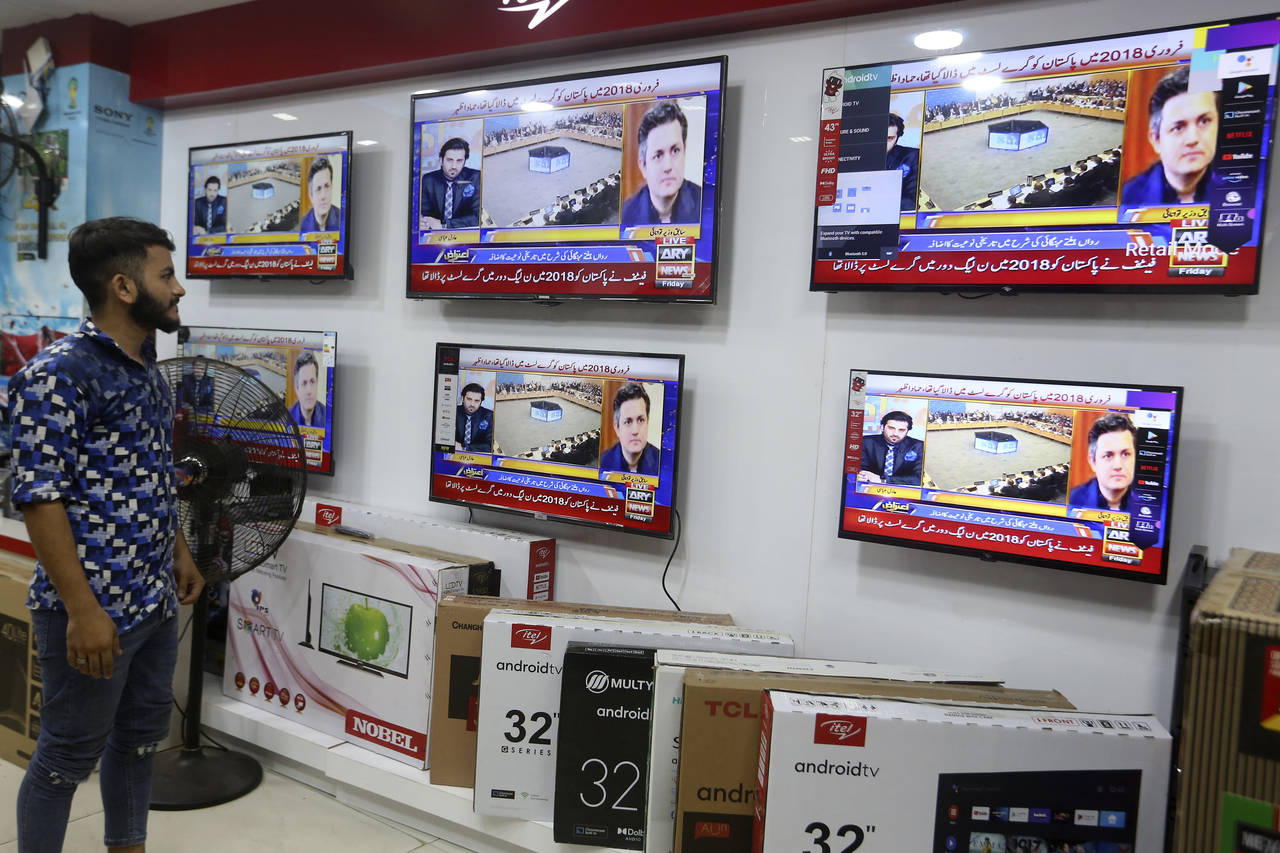 A Pakistan watches news channel flashing news regarding FATF decision, at a market in Karachi, Paki...