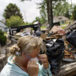 
              Melody Murter puts on a mask while helping to clean out a friend's home after it was damaged by severe flooding in Fromberg, Mont., Friday, June 17, 2022. (AP Photo/David Goldman)
            