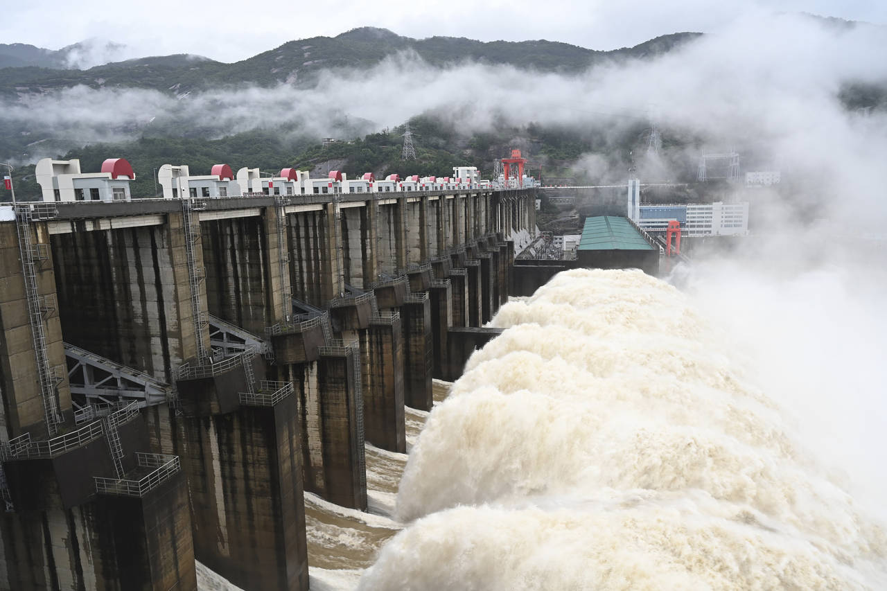 In this photo released by China's Xinhua News Agency, water flows out from a gate of the Shuikou Hy...