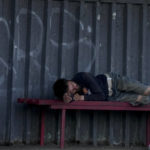 
              A homeless man sleeps on a bench at a bus stop on the outskirts of Kyiv, Ukraine, Thursday, June 9, 2022. (AP Photo/Natacha Pisarenko)
            