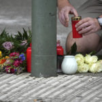 
              A person puts a candle on the floor between flowers and candles at the Kaiser Wilhelm Memorial Church in Berlin, Germany, Thursday, June 9, 2022. On Wednesday June 8, a 29-year-old man drove his car into a group of students killing their teacher and crash into a store. (AP Photo/Michael Sohn)
            