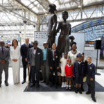 
              Britain's Prince William and Kate, Duchess of Cambridge pose for a photo with Trinidad born writer and TV personality Floella Benjamin, Windrush passengers Alford Gardner and John Richards and children, during the unveiling of the National Windrush Monument at Waterloo Station in London, Wednesday, June 22, 2022. The unveiling of the statue - of a man, woman and child in their Sunday best standing on top of suitcases on Wednesday will mark Windrush Day. (John Sibley/Pool Photo via AP)
            