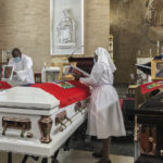 
              Church officials set up photos of the 11 Haitian women who died last month when the overloaded boat they were in capsized, at a church in San Juan, Puerto Rico, Wednesday, June 15, 2022. The boat was carrying an estimated 60 to 75 migrants, of which eleven were found dead, at least a dozen still missing and 38 rescued. (AP Photo/Dánica Coto)
            