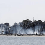 
              Smoke rises from the charred remains of trees at the north end of St. Catherine's Island, Wednesday, June 22, 2022. Four separate fires sparked by lightning strikes have burned on the Island since June 11. The Georgia Forestry Commission is working to control the spread of the fire while preserving the historical significance of the island. (Richard Burkhart/Savannah Morning News via AP)
            