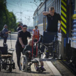 
              Police officers help a disabled elderly woman get into an evacuation train after she was evacuated from the Lysychansk area in Pokrovsk in eastern Ukraine, Saturday June 11, 2022. (AP Photo/Efrem Lukatsky)
            