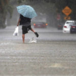 
              A person walks down a flooded street in Hallandale Beach, Fla., Saturday June 4, 2022, on Saturday, June 4, 2022. (Mike Stocker/South Florida Sun-Sentinel via AP)
            