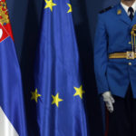 
              FILE - A member of the Serbian honour guard stands by Serbian, left, and EU flags during visit of Greek President Prokopis Pavlopoulos in Belgrade, Serbia, Monday, Oct. 2, 2017. European Union leaders will seek to offer support this week to six Western Balkan nations that have long been knocking at the bloc's doors, and now see the war in Ukraine raging not far from their borders amid fears that Russia could turn its sights on their region. Serbia, the largest of the six countries, is pivotal in Russia's regional influence. (AP Photo/Darko Vojinovic, File)
            