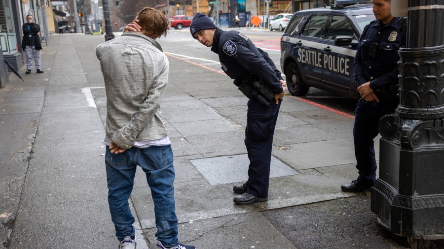 Police officers check on a man who said he has been smoking fentanyl in downtown Seattle on March 1...