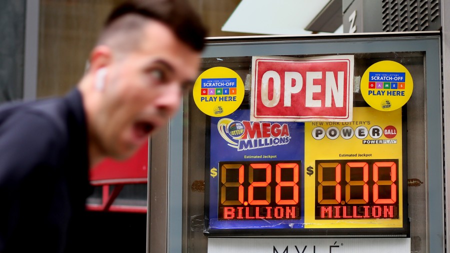 A man rides a bike past advertisements for the Mega Millions and Powerball lottery on July 29, 2022...