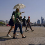 
              A woman holds an umbrella to shelter from the sun, as she walks on the south bank of river Thames, in London, Monday, July 18, 2022. Britain’s first-ever extreme heat warning is in effect for large parts of England as hot, dry weather that has scorched mainland Europe for the past week moves north, disrupting travel, health care and schools. (AP Photo/Alberto Pezzali)
            