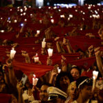 
              Revelers dressed in white and red color hold candles and kerchiefs as they sing San Fermin's song ''Pobre de Mi'' to close nine days of the running of the bulls, music and dance, at the San Fermin Festival, in Pamplona, northern Spain, early Friday, July 15, 2022. (AP Photo/Alvaro Barrientos)
            