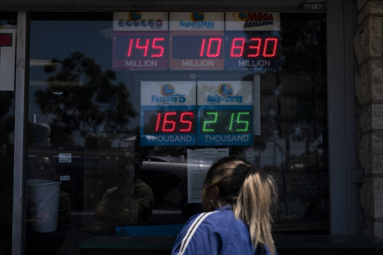 A woman peeks through the window of Blue Bird Liquor while waiting in line to purchase a Mega Milli...