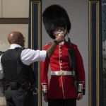 
              A police officer givers water to a British soldier wearing a traditional bearskin hat, on guard duty outside Buckingham Palace, during hot weather in London, Monday, July 18, 2022. The British government have issued their first-ever "red" warning for extreme heat. The alert covers large parts of England on Monday and Tuesday, when temperatures may reach 40 degrees Celsius (104 Fahrenheit) for the first time, posing a risk of serious illness and even death among healthy people, the U.K. Met Office, the country's weather service, said Friday. (AP Photo/Matt Dunham)
            