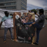 
              A pro-Rohingya demonstrator kicks an image senior general Min Aung Hlaing, Myanmar military governor, outside the International Court of Justice in The Hague, Netherlands, Friday, July 22, 2022, where judges rule on whether a case brought by Gambia alleging that Myanmar is committing genocide against the Rohingya can go ahead. Myanmar argues that the court does not have jurisdiction. (AP Photo/Peter Dejong)
            