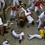 
              Runners fall during the running of the bulls at the San Fermin Festival in Pamplona, northern Spain, Monday, July 11, 2022. Revellers from around the world flock to Pamplona every year for nine days of uninterrupted partying in Pamplona's famed running of the bulls festival which was suspended for the past two years because of the coronavirus pandemic. (AP Photo/Alvaro Barrientos)
            
