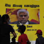 
              People watch propaganda materials displayed against prime minister Ranil Wickremesinghe outside president Gotabaya Rajapaksa's office three days after it was stormed by anti government protesters in Colombo, Sri Lanka, Tuesday, July 12, 2022. (AP Photo/Eranga Jayawardena)
            