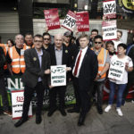 
              General Secretary Mick Lynch, centre and Eddie Dempsey, centre right, Assistant General Secretary, of the Rail, Maritime and Transport union (RMT), stand outside London Euston train station as union members take part in a fresh strike over jobs, pay and conditions, Wednesday July 27, 2022. (Aaron Chown/PA via AP)
            