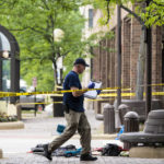
              Members of the FBI's Evidence Response Team Unit investigate on Central Avenue near Green Bay Road in downtown Highland Park, Ill., less than 24 hours after a gunman killed several people and wounded dozens more by firing a high-powered rifle from a rooftop onto a crowd attending Highland Park's Fourth of July parade, Tuesday morning, July 5, 2022. (Ashlee Rezin/Chicago Sun-Times via AP)
            