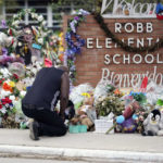 
              FILE - Reggie Daniels pays his respects at a memorial at Robb Elementary School in Uvalde, Texas, on June 9, 2022, honoring the two teachers and 19 students killed in the shooting at the school on May 24. For families fractured along red house-blue house lines, summer’s slate of reunions and weddings poses another round of tension. Pandemic restrictions have melted away but gun control, the fight for reproductive rights, the Jan. 6 insurrection hearings, who's to blame for soaring inflation and a range of other issues continue to simmer. (AP Photo/Eric Gay, File)
            