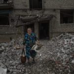 
              A woman salvages what she can from her home, after a rocket hit an apartment residential block, in Chasiv Yar, Donetsk region, eastern Ukraine, Sunday, July 10, 2022. At least 15 people were killed and more than 20 people may still be trapped in the rubble, officials said Sunday. (AP Photo/Nariman El-Mofty)
            