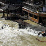 
              FILE - Flood waters sweep through the ancient town of Feng Huang in central China's Hunan province, Saturday, June 4, 2022. Flooding and extreme high temperatures have caused multiple deaths in eastern China as summer heat descends earlier than usual. (AP Photo, File)
            