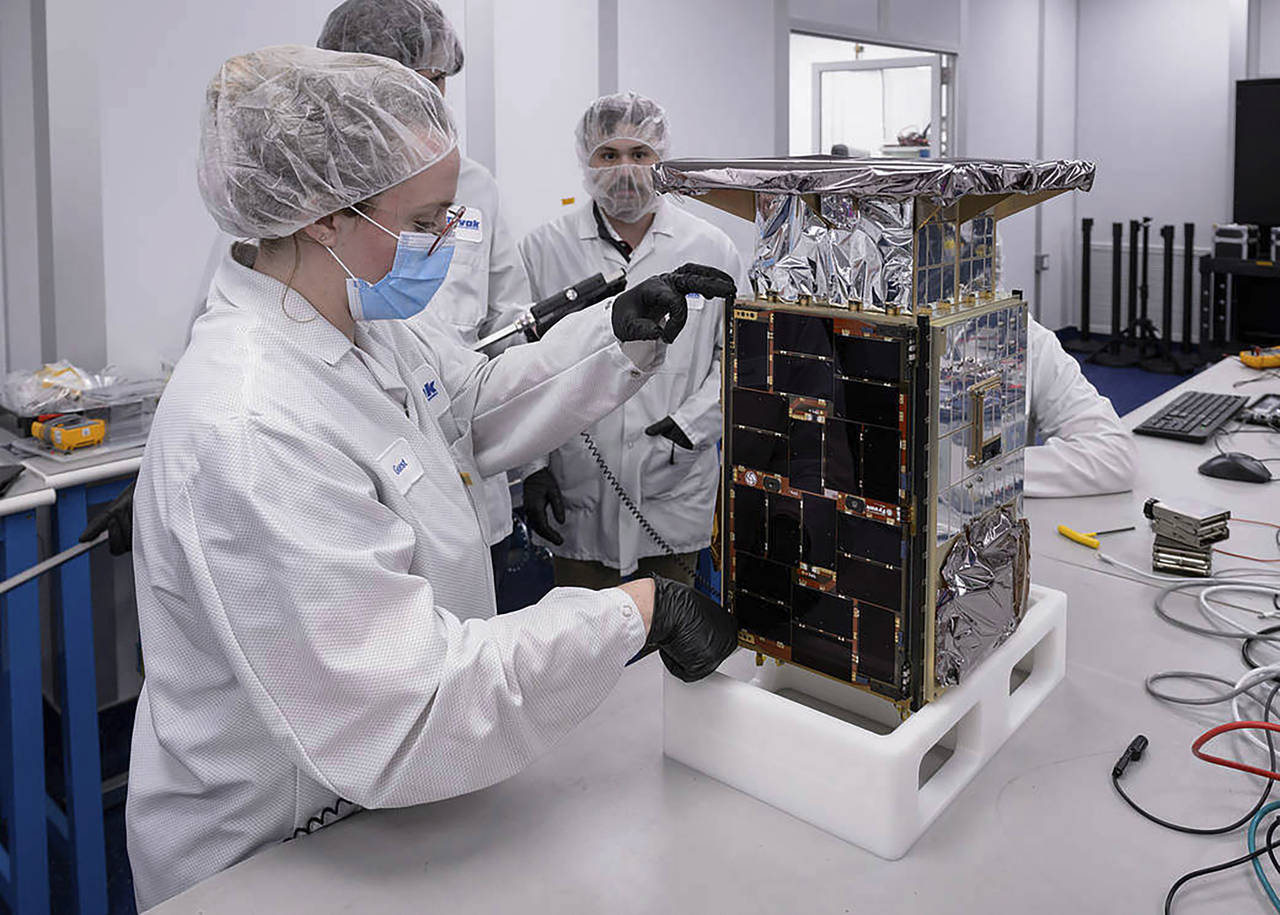 Rebecca Rogers, systems engineer, left, takes dimension measurements of the CAPSTONE spacecraft in ...