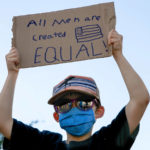 
              FILE - A boy holds a sign saying "All men are created equal," as he attends a protest on June 7, 2020, near the White House in Washington, over the death of George Floyd, a black man who was in police custody in Minneapolis. “All men are created equal.” Few words in American history are invoked as often as the preamble to the Declaration of Independence, published nearly 250 years ago, and few more difficult to define. (AP Photo/Jacquelyn Martin, File)
            