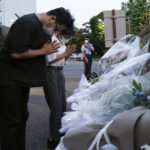 
              Mourners offer flowers for former Japanese Prime Minister Shinzo, at the entrance of the Liberal Democratic Party (LDP) headquarters building in Tokyo, Japan, Sunday, July 10, 2022. Japan is holding elections in the shadow of the assassination of former Prime Minister Shinzo Abe, gunned down while making a campaign speech. (Toru Hana/Pool via AP)
            