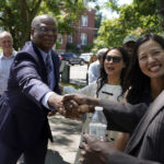 
              Michael Cox, left, who has been named as the next Boston police commissioner, shakes hands while greeting people as Boston Mayor Michelle Wu, right, looks on as they arrives at a news conference, Wednesday, July 13, 2022, in Boston's Roxbury neighborhood. Cox, who was beaten more than 25 years ago by colleagues who mistook him for a suspect in a fatal shooting, served in multiple roles with the Boston Police Department before becoming the police chief in Ann Arbor, Michigan, in 2019. (AP Photo/Steven Senne)
            