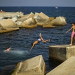 
              Youngsters dive into the Mediterranean sea during a hot sunny day in Barcelona, Spain, Thursday, July 21, 2022. (AP Photo/Francisco Seco)
            