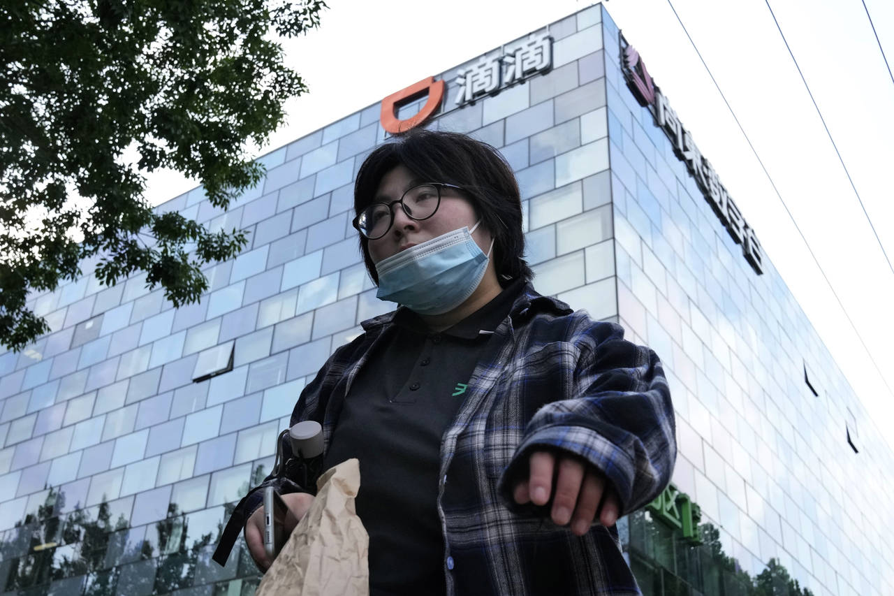 FILE - A woman walks past the headquarters for Didi Beijing on July 16, 2021. China’s internet wa...